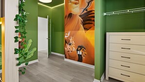 A hallway with green walls, a wooden door, a white cabinet, and a mural of animated characters.