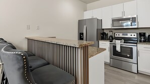 A modern kitchen with white cabinets, stainless steel appliances, and a built-in island with seating.