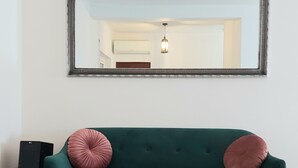 A living room with a green sofa, two pink pillows, a wooden coffee table, a black speaker, and a large mirror on the wall. - Vacation home Casa Rose, affordable accommodation (4 pers), ideal for long-term vacation. (Luz)