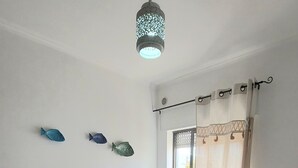 A neatly made bed with a white bedspread and pillows, a hanging light fixture, and three decorative fish on the wall. - Vacation home Casa Rose, affordable accommodation (4 pers), ideal for long-term vacation. (Luz)