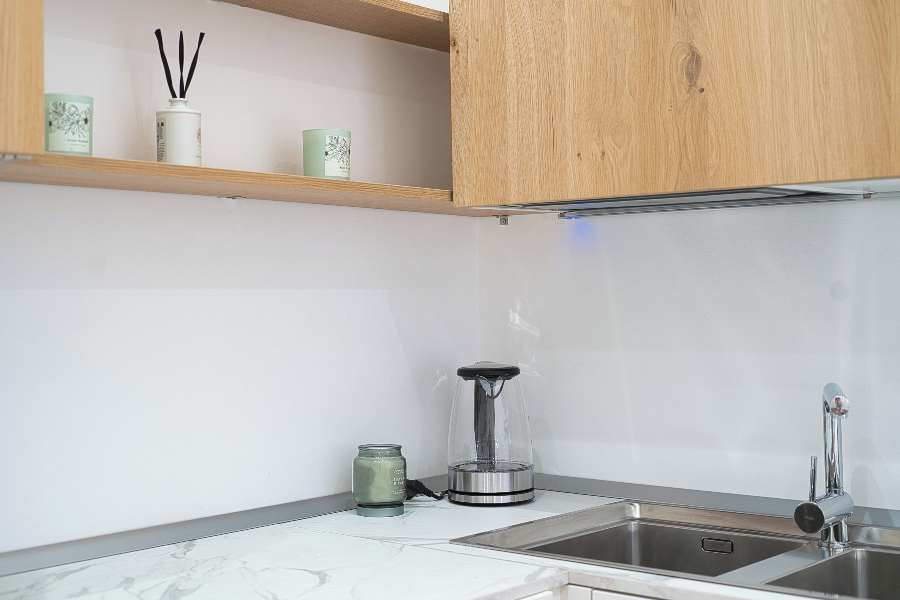 A kitchen with a double sink, a coffee maker, and a shelf with decorative items.