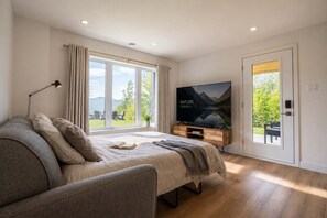 A bedroom with a bed, a TV, a window, and a door leading to an outdoor area. - Mountain View & Spa | Chalet Le Albert (Saint-Côme)