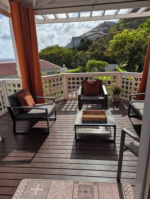 A covered outdoor seating area with a view of a hilltop building.
