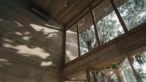 Una habitación con techo alto, vigas de madera y ventanas amplias que dejan entrar luz natural.