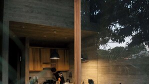 Una cocina moderna con armarios de madera, una isla central con taburetes y vistas al exterior a través de un ventanal.