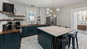 Une cuisine moderne avec des meubles de couleur sombre, un plan de travail en marbre et un îlot central doté de tabourets de bar.