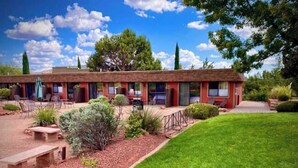 A motel with a row of rooms, outdoor seating, and a well-maintained lawn. - A comfortable studio facing the breathtaking Red Rocks. (Sedona)
