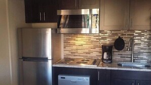 A modern kitchen with stainless steel appliances, dark cabinetry, and a tiled backsplash. - Spacious studio with full kitchen and unobstructed views (Sedona)