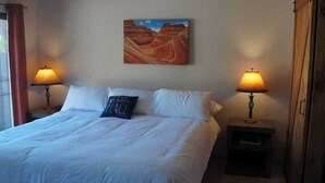 A neatly made bed with white linens and a single decorative pillow, flanked by two bedside lamps. - Spacious studio with full kitchen and unobstructed views (Sedona)