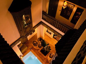 A high-ceilinged atrium with a central pool, a staircase with a balustrade, and a seating area with plants. - Riad KAYA & SPA (Marrakech)