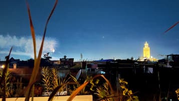 Vista nocturna de una ciudad con una torre iluminada destacada al fondo.