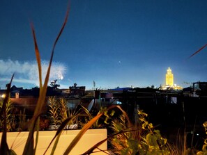 A nighttime view of a cityscape with a prominent illuminated tower in the background. - Riad KAYA & SPA (Marrakech)