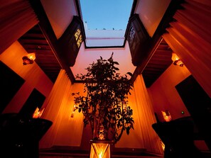 A room with a skylight, a potted plant, and two side tables with candles. - Riad KAYA & SPA (Marrakech)