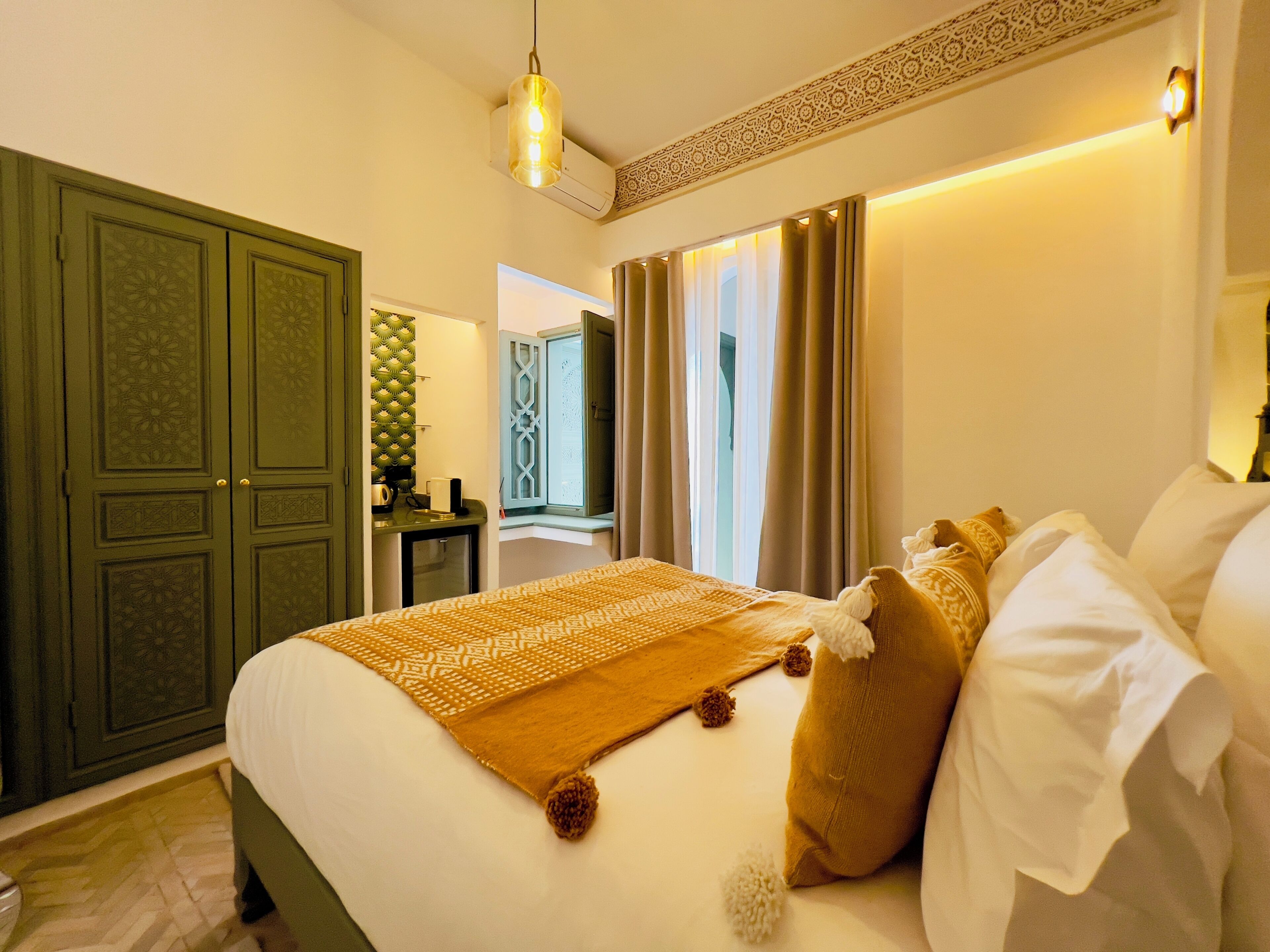 Une chambre d’hôtel avec un grand lit, une armoire, un bureau et une fenêtre avec des rideaux.