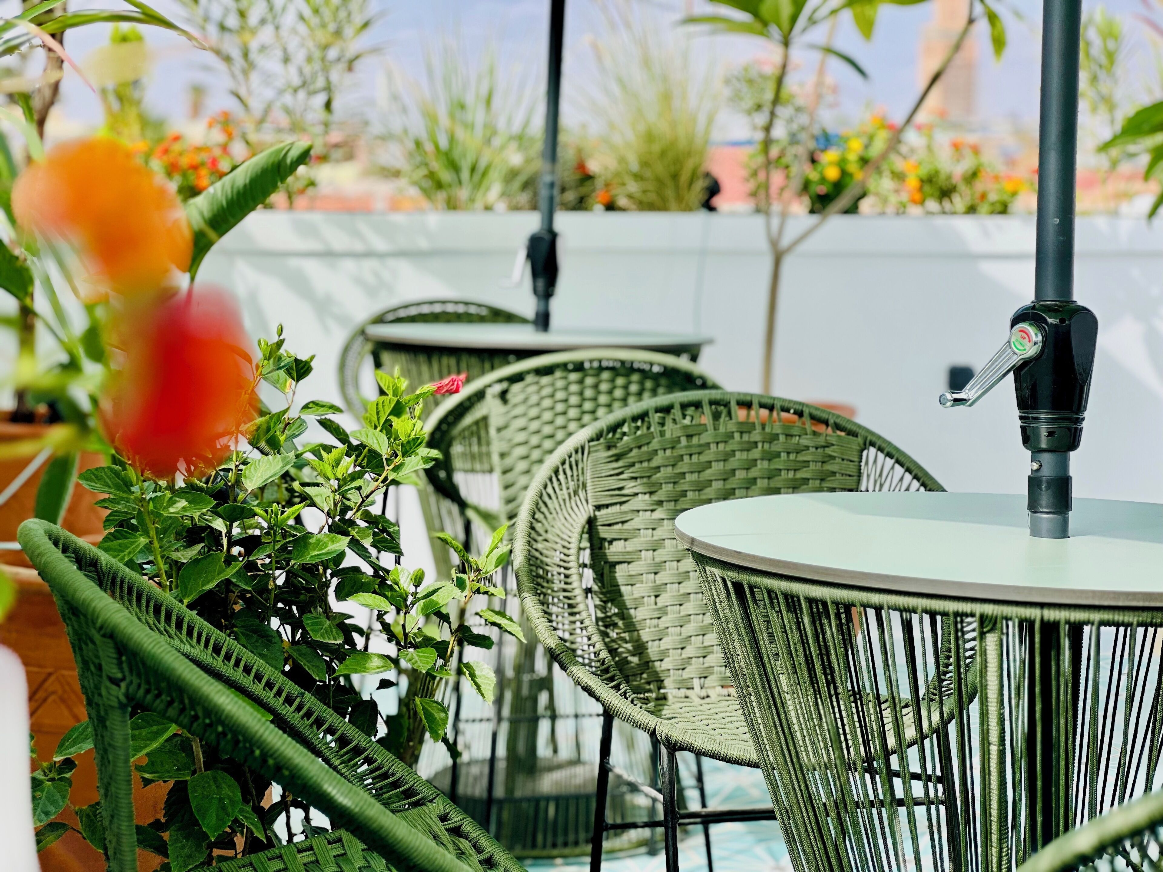 A patio area with wicker chairs and a table, a water fountain, and potted plants.