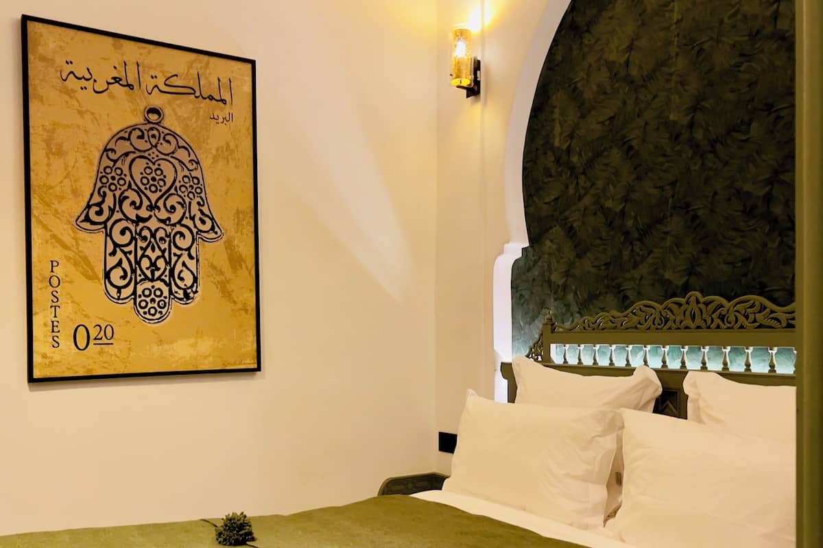 A hotel room with a bed, a wall-mounted artwork, and a decorative wall panel.