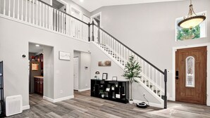 A spacious living area with a wooden floor, a staircase, a kitchen, and a dining area.