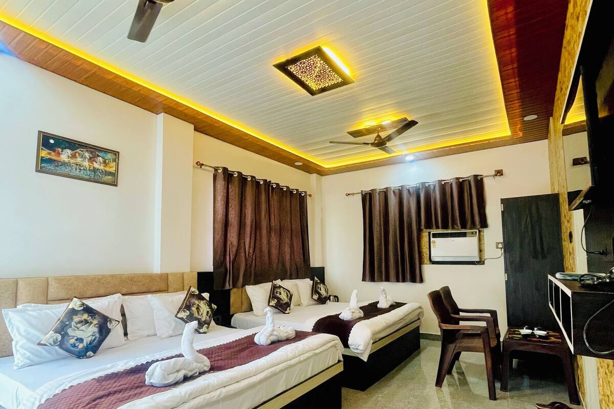A hotel room with two beds, a ceiling fan, a TV, and a small desk.