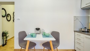 A compact kitchen with a white table, two grey chairs, and a small dining area.