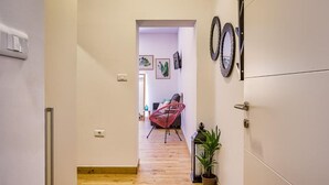 A hallway with wooden flooring, a potted plant, and a red chair.