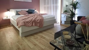 A modern bedroom with a bed, bedside table, and a mirror.
