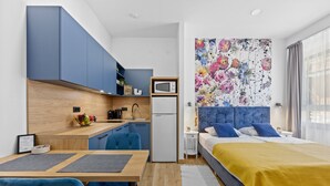 A compact bedroom with a bed, a bedside table, and a large floral artwork on the wall.