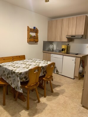 A compact kitchen with a dining table, chairs, a coffee maker, and a built-in dishwasher.