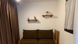 Ein gemütliches Zimmer mit einer Holzsofa, einem kleinen Holztisch und zwei Wandregalen.