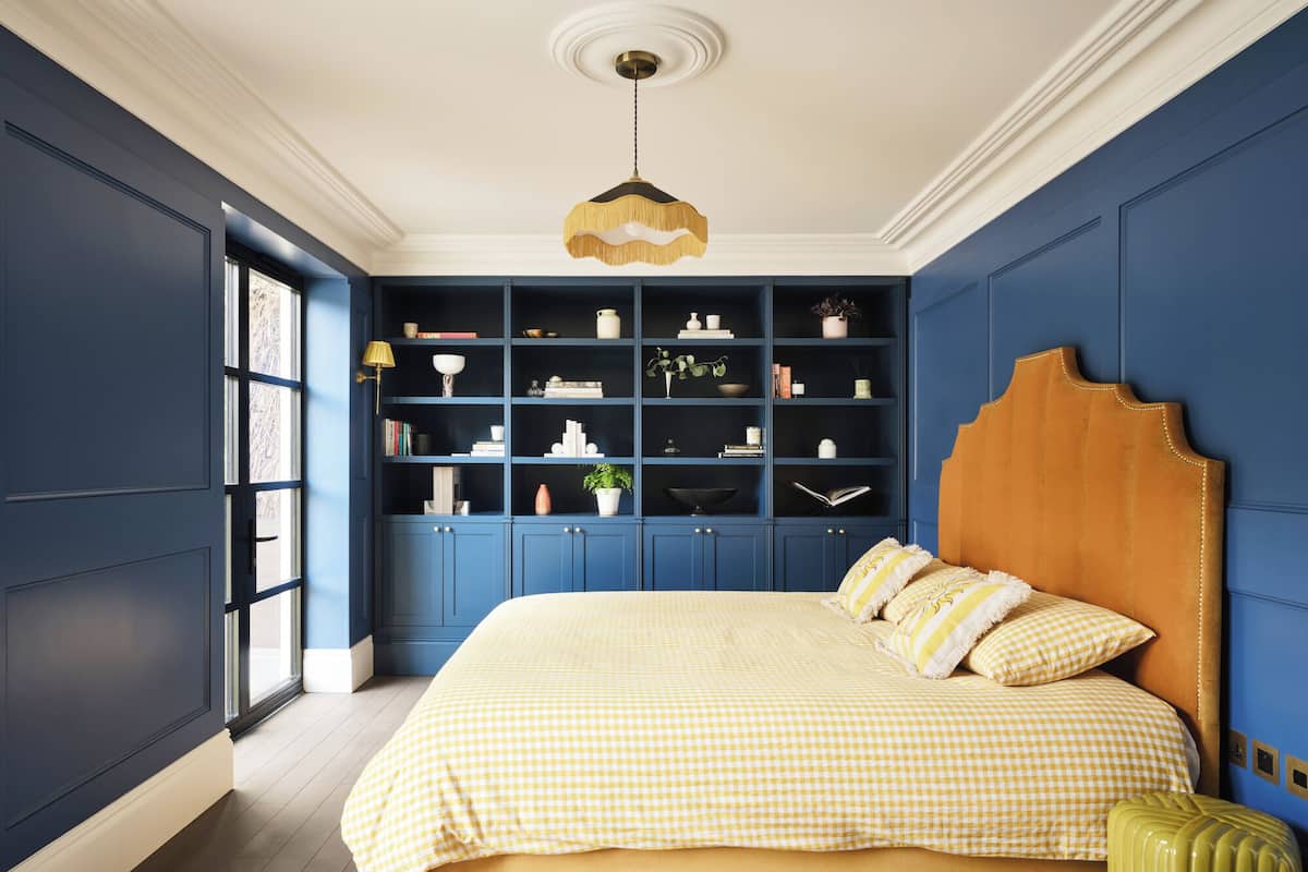 A bedroom with a large bed, built-in shelving, and a unique headboard.
