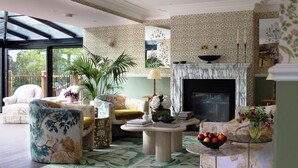 A cozy living room with floral patterned wallpaper, a fireplace, and comfortable seating. - Thames Mansion - River View (Windsor)