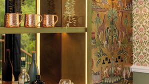 A kitchen with a marble countertop, a gold-framed shelf with decorative items, and a patterned wallpaper. - Thames Mansion - River View (Windsor)
