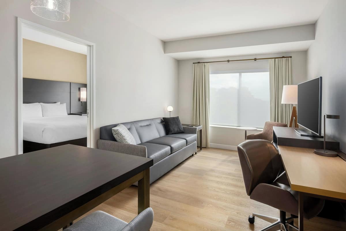 Et moderne hotelværelse med seng, sofa, spisebord og tv.