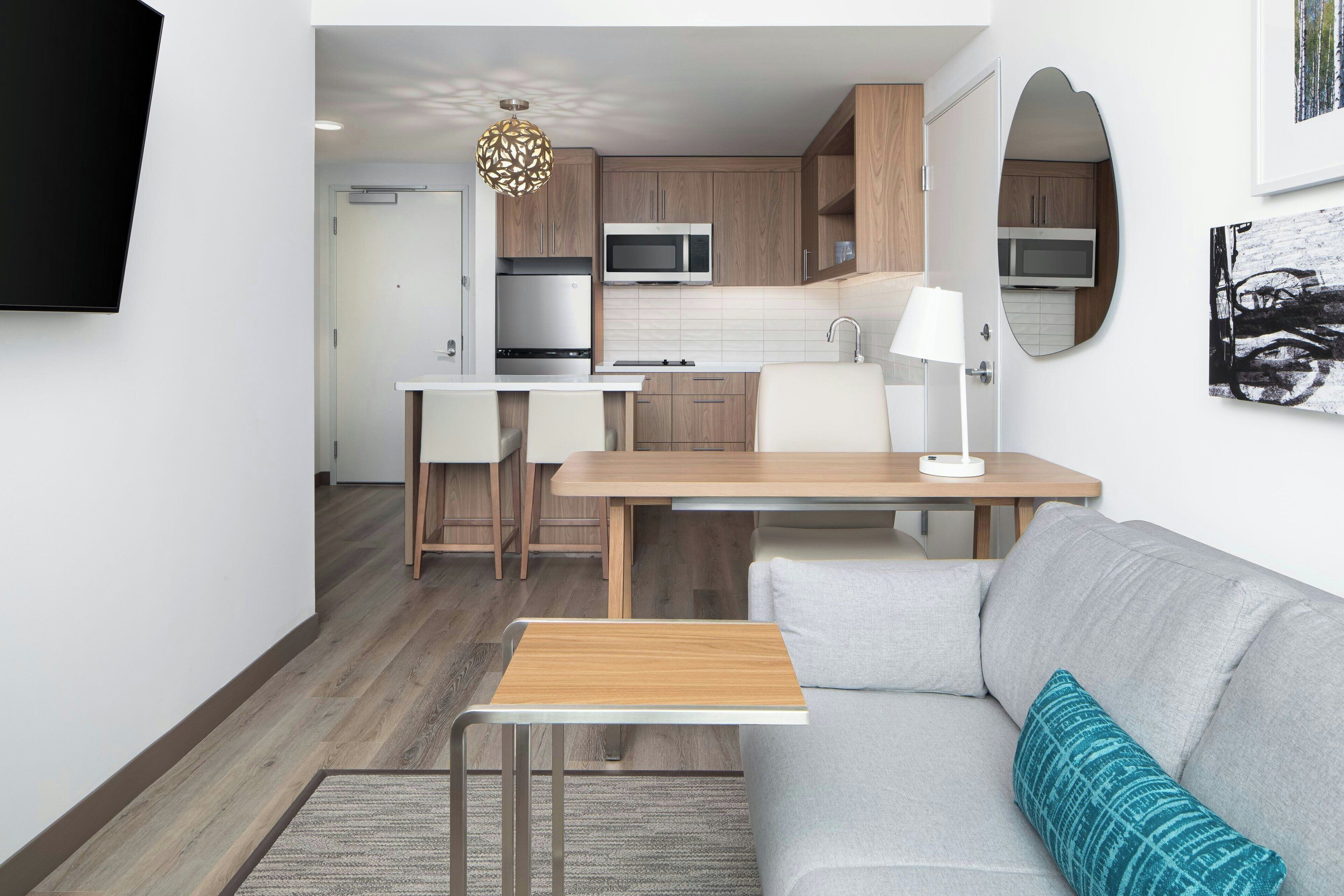 A compact living space with a kitchenette, a dining area, and a seating area with a sofa and a small table.