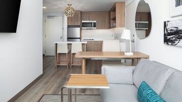 A compact living space with a kitchenette, a dining area, and a seating area with a sofa and a small table.