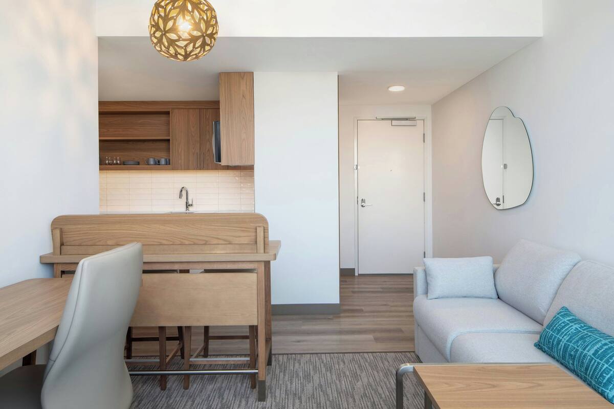 A modern kitchen with wooden cabinets, a sink, and a dining area with a bench and chairs.