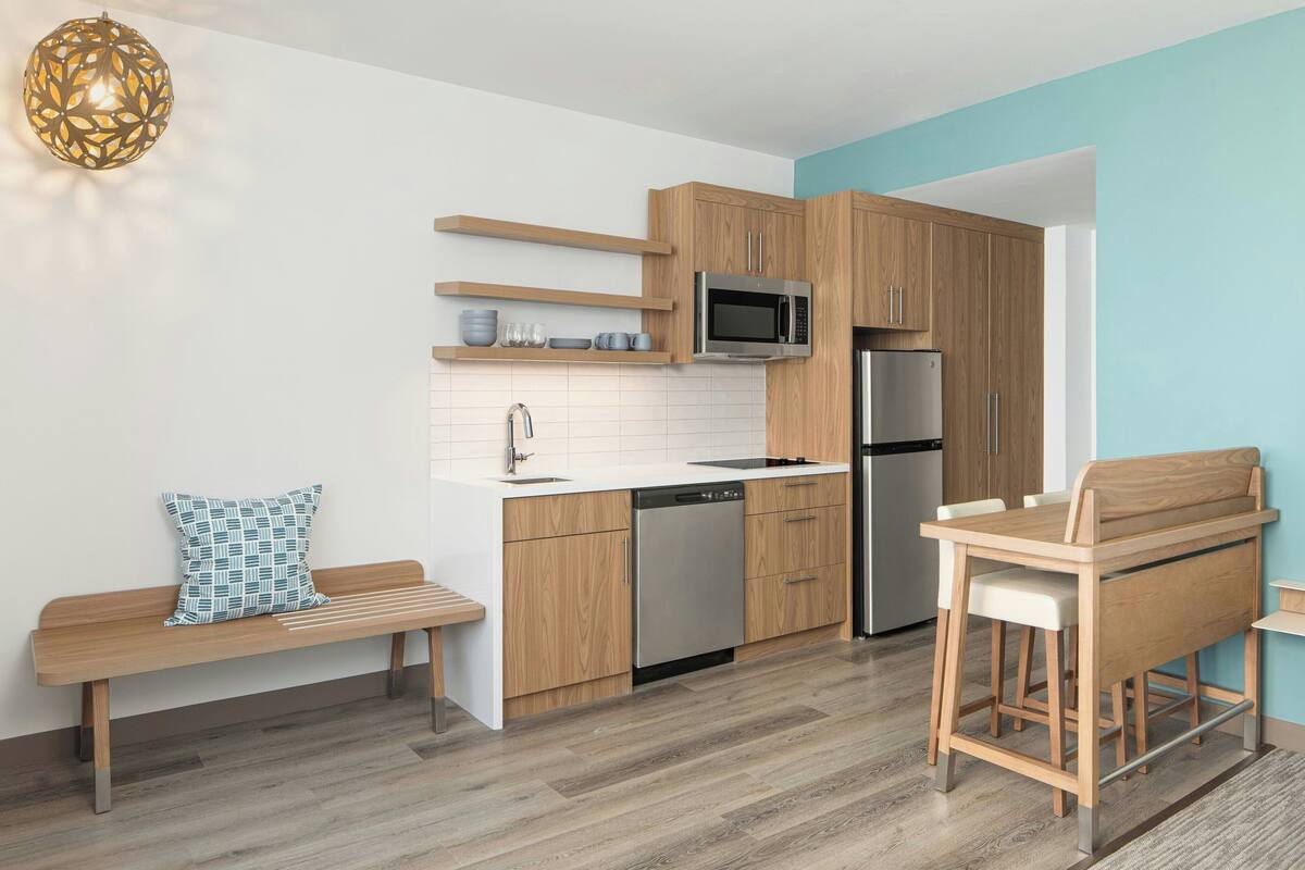 A modern kitchen with wooden cabinets, a built-in microwave, and a stainless steel refrigerator.