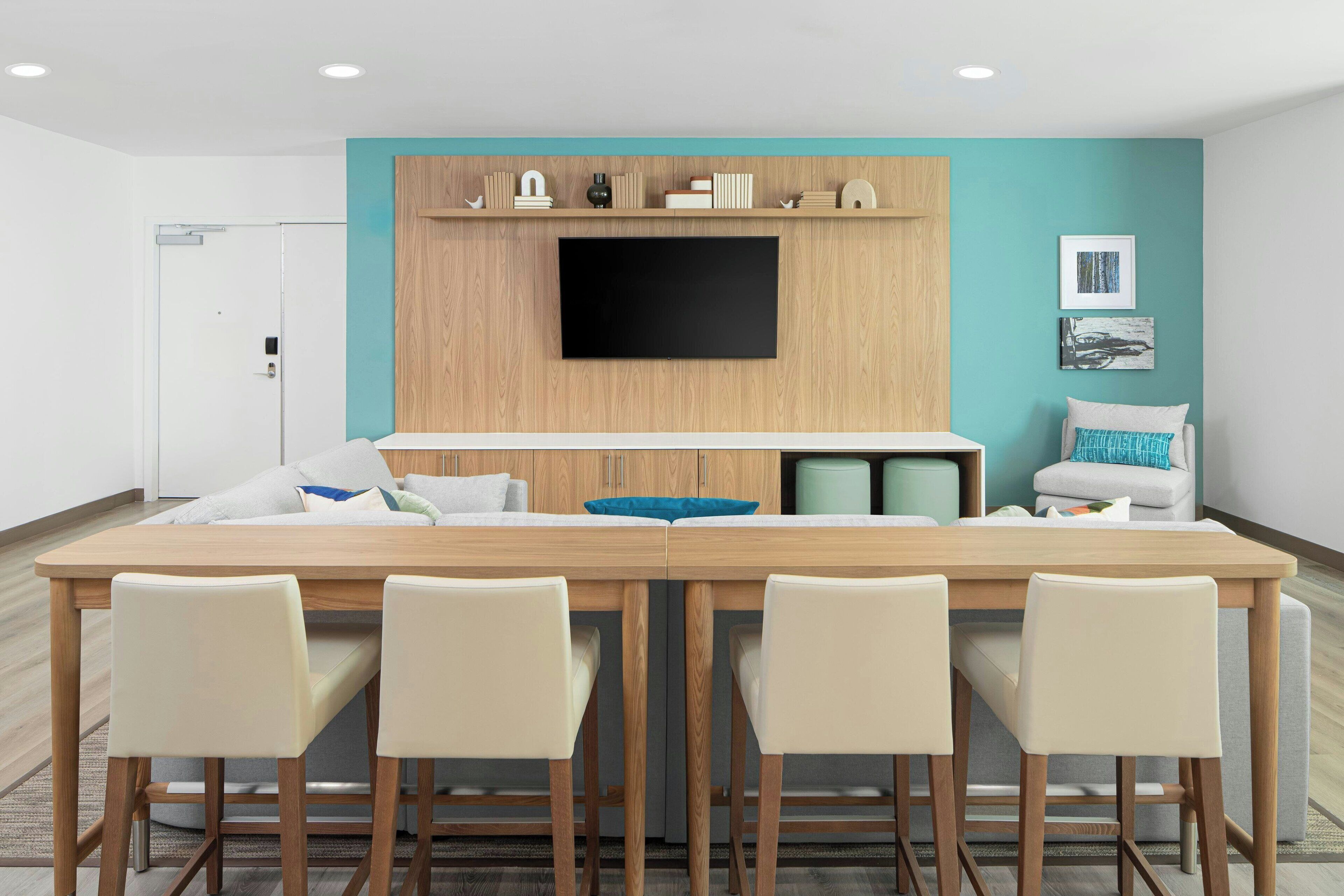 Una cocina moderna con televisión de pantalla plana, armarios de madera y una pared de acento color aguamarina.