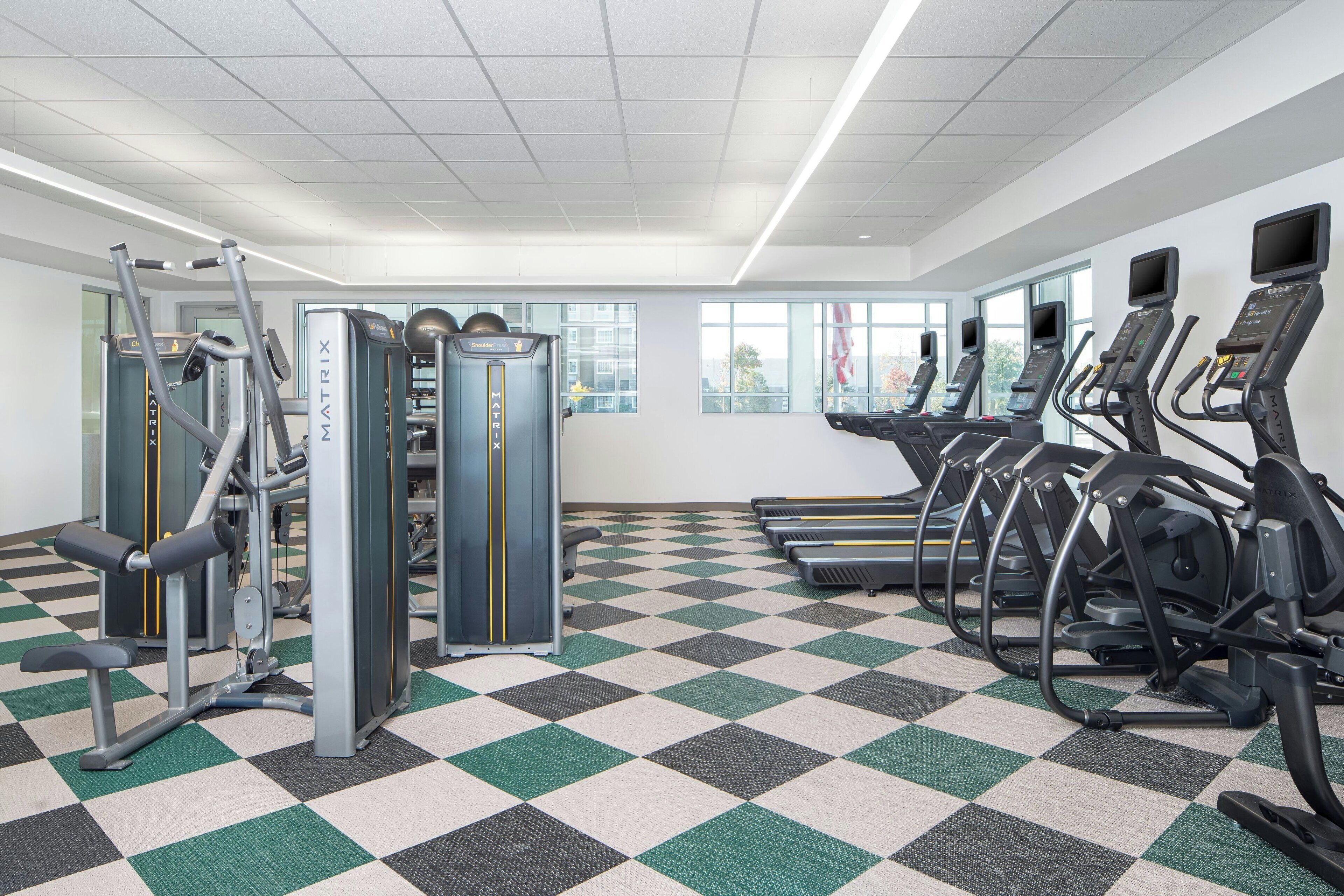 Un gimnasio con cintas de correr, elípticas y equipo de pesas.