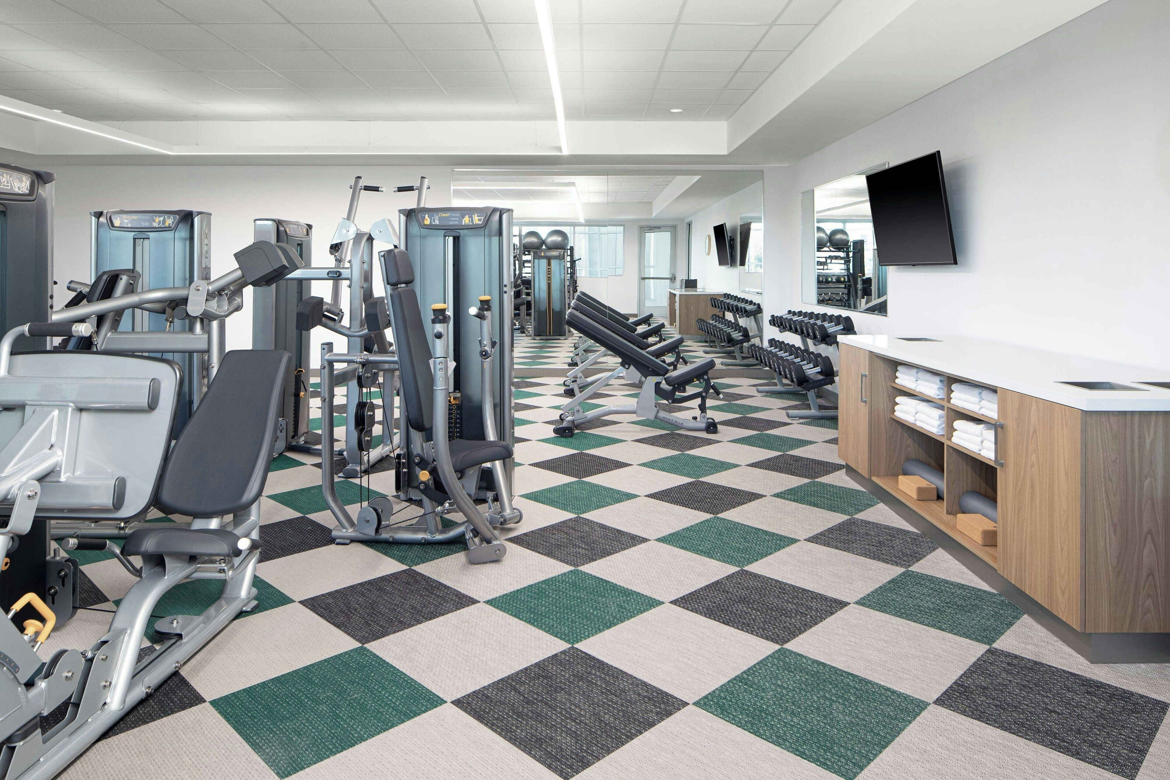 A gym with various exercise machines, a check-in counter, and a large mirror.