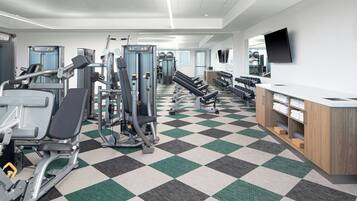 A gym with various exercise machines, a check-in counter, and a large mirror.