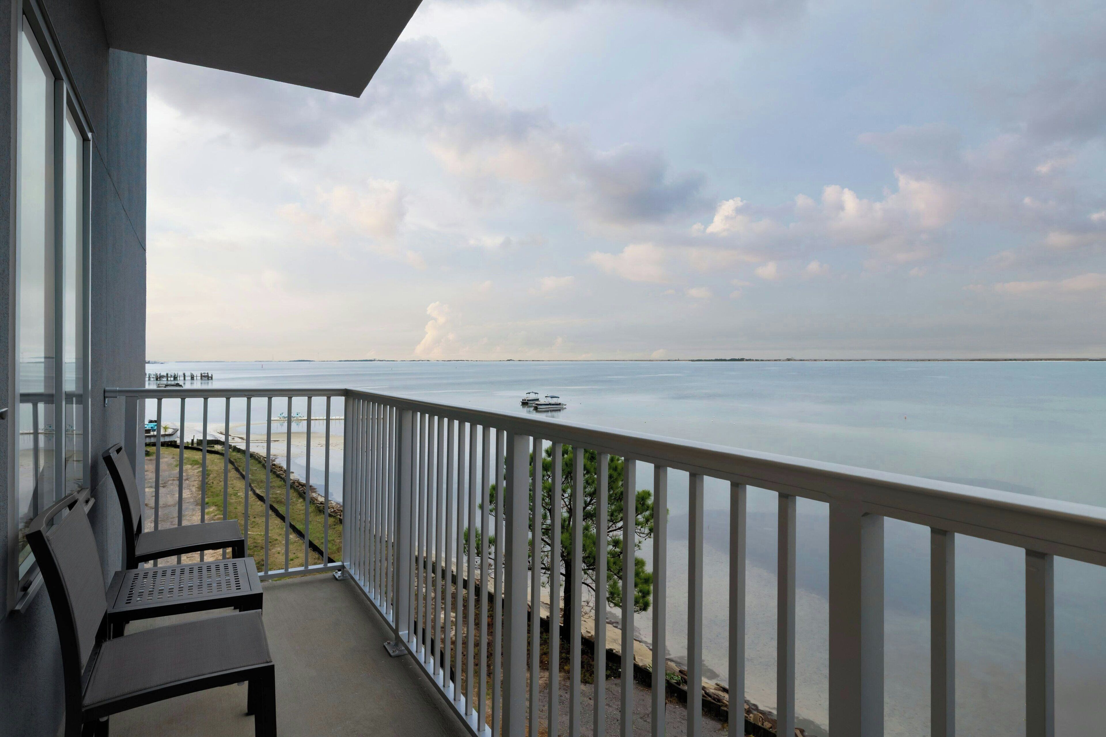 A balcony with a view of the sea, a bench, and a railing.