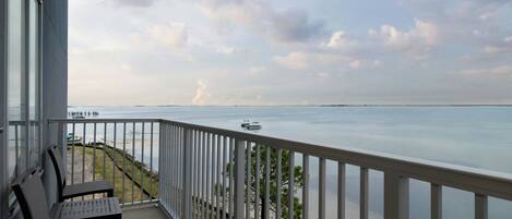 A balcony with a view of the sea, a bench, and a railing.
