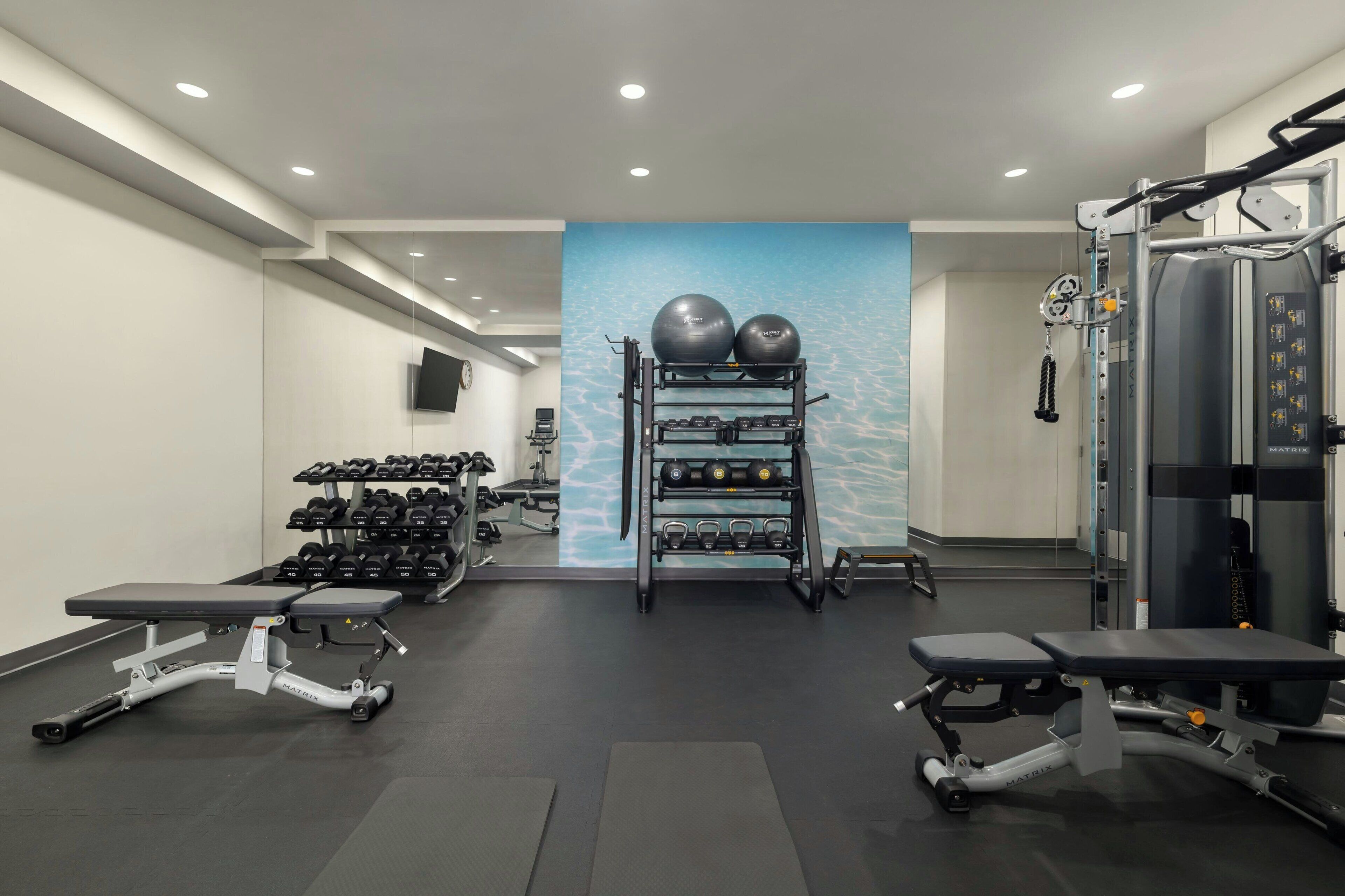 Un gimnasio con bancos para pesas, mancuernas y equipamiento de ejercicio.