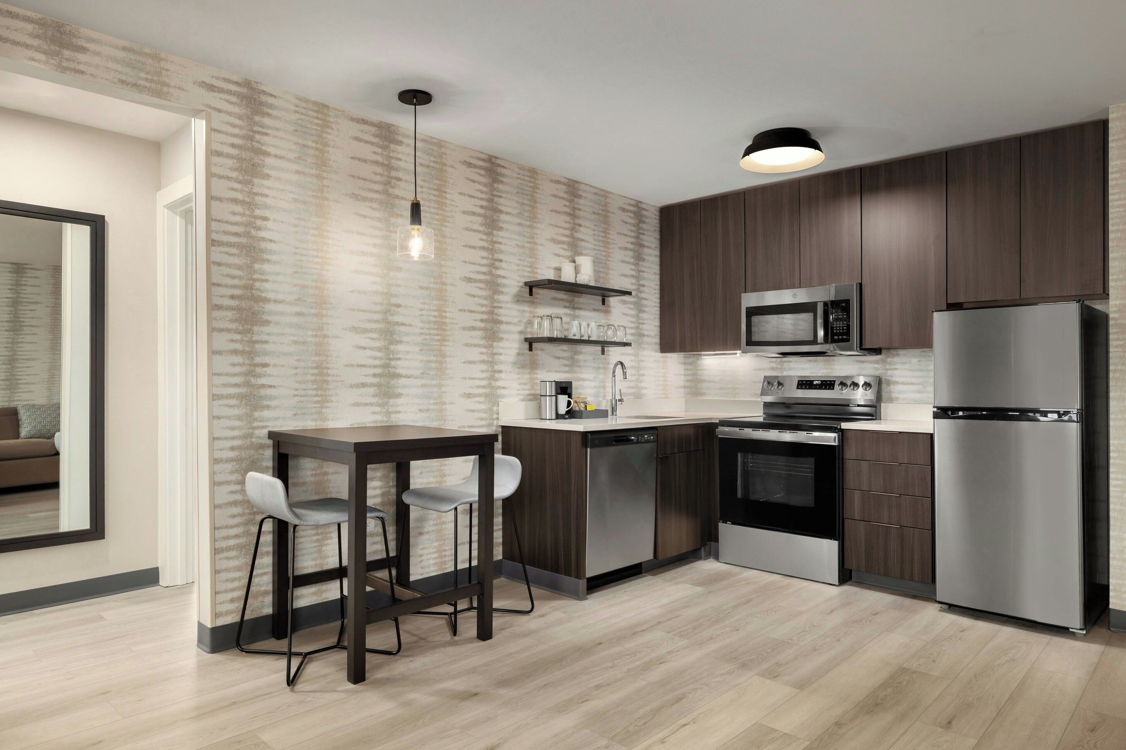 A modern kitchen with dark wood cabinets, stainless steel appliances, and a light wood floor.