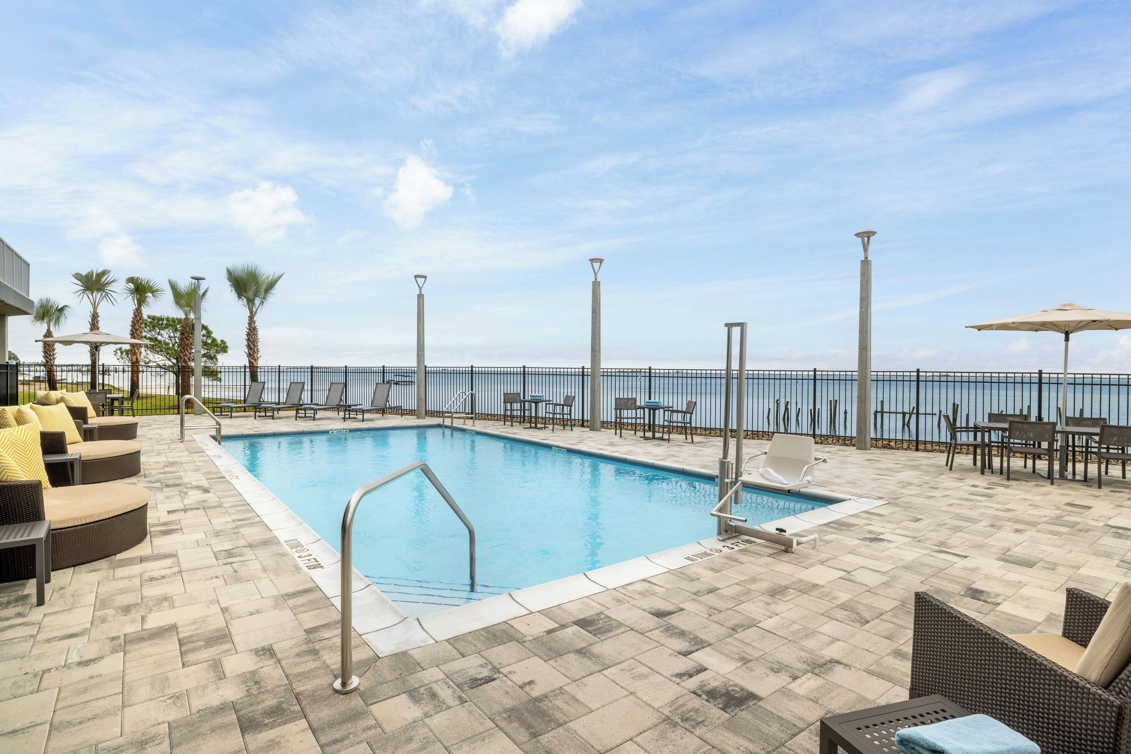Un espace aménagé au bord de la piscine, avec des chaises longues, une piscine et une vue sur la mer.