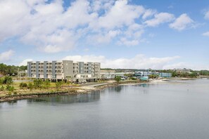 A multi-story hotel with balconies, situated by a calm body of water, with a clear sky above. - Residence Inn By Marriott Navarre Waterfront (Navarre)