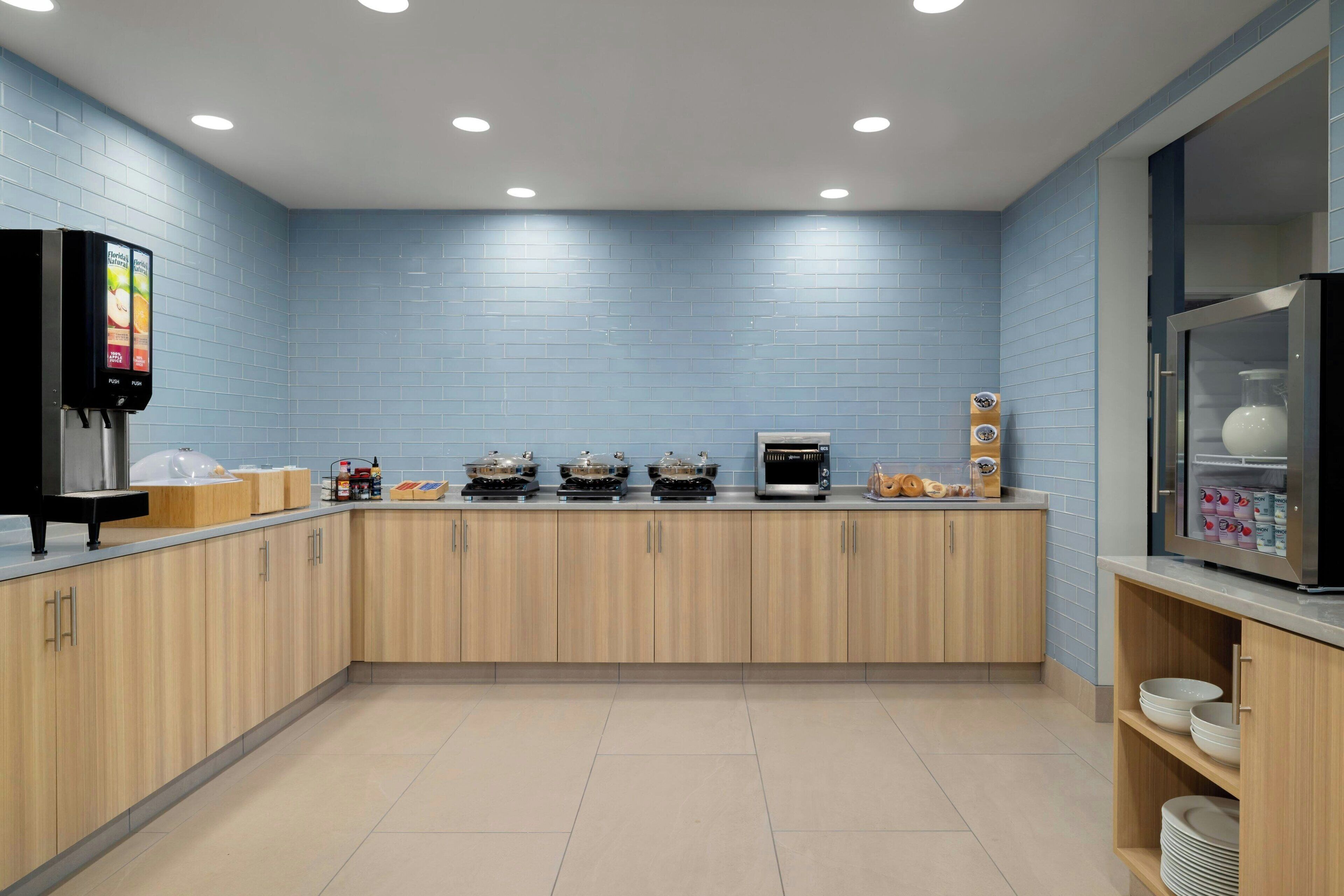 Una cocina moderna con armarios de madera clara, un microondas integrado y una cafetera.