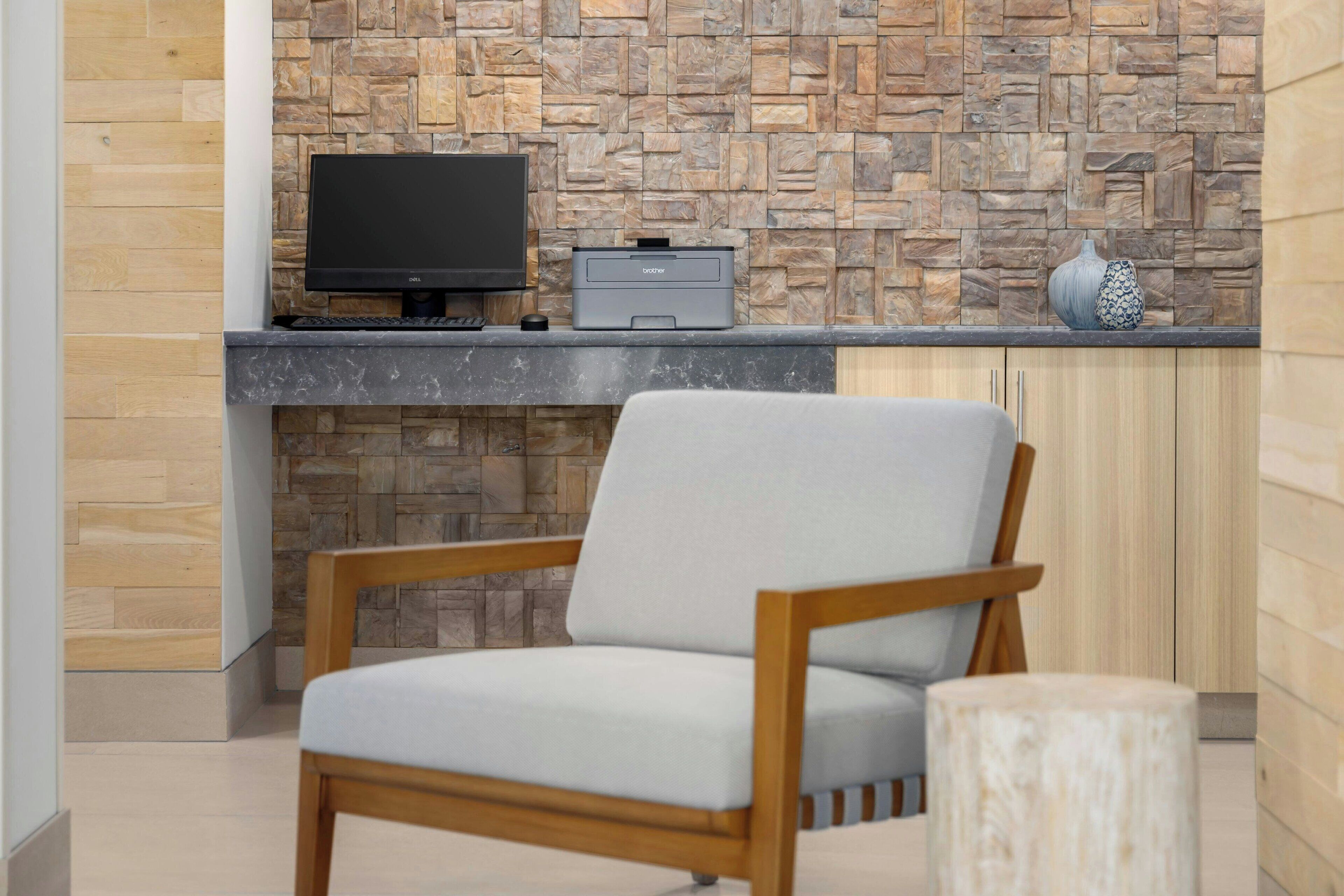 A modern room with a stone wall, a flat-screen TV, a printer, and a wooden chair.