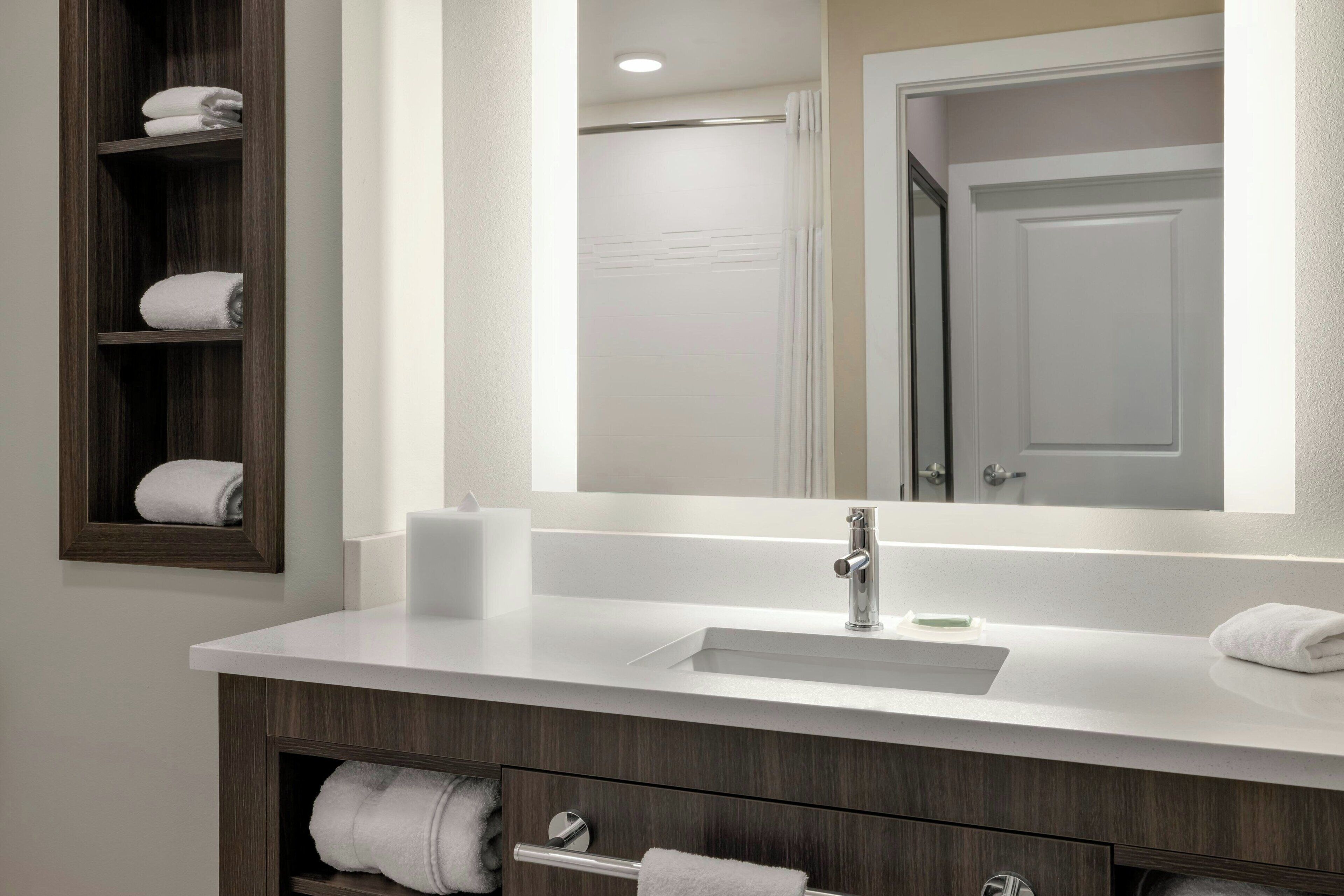 A modern bathroom with a white sink, dark wood vanity, and a large mirror.