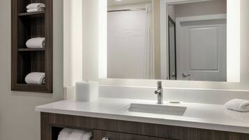 A modern bathroom with a white sink, dark wood vanity, and a large mirror.